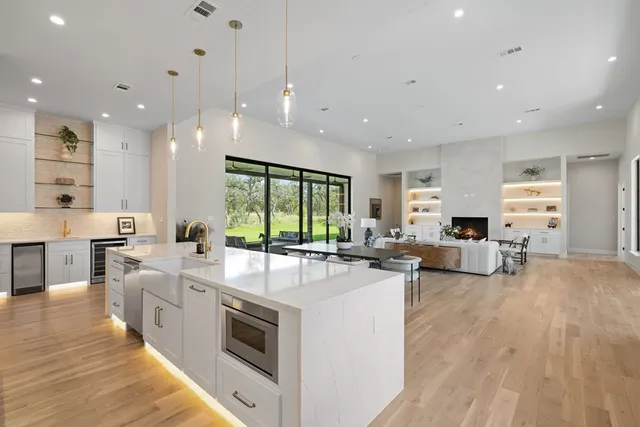 a large white kitchen with lots of counter space a sink appliances and a large window
