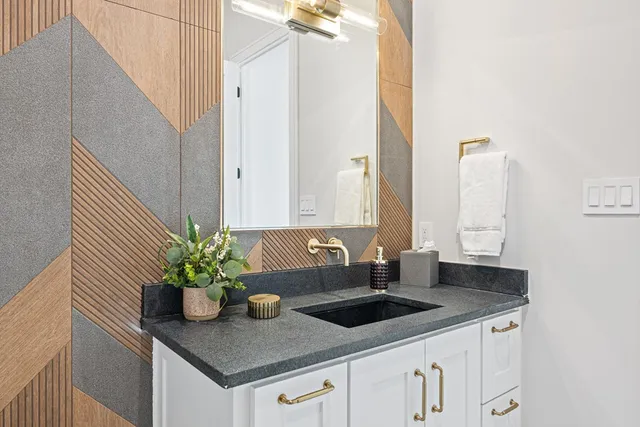 a bathroom with a granite countertop sink and a white cabinets