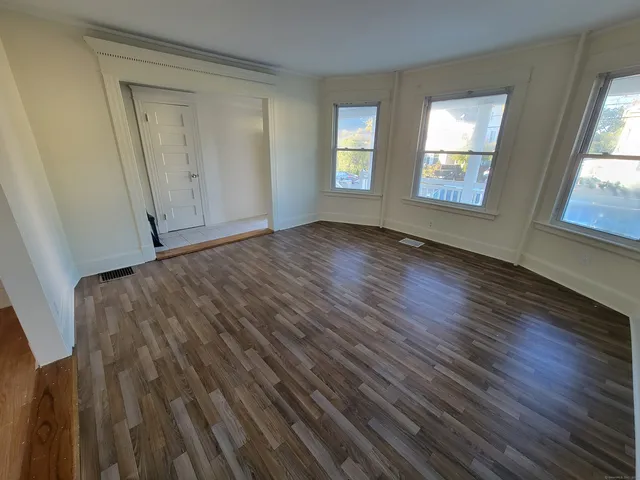 a view of an empty room with wooden floor and window