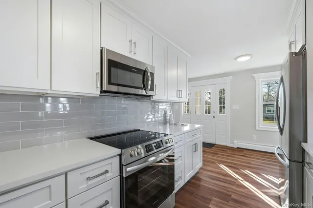 a kitchen with stainless steel appliances granite countertop white cabinets a microwave oven a sink and dishwasher