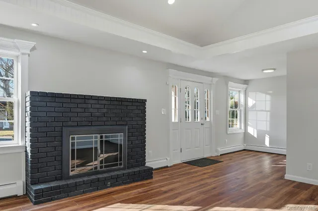 a view of an empty room with wooden floor fireplace and a window