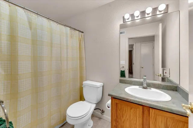 a bathroom with a granite countertop sink a toilet and a mirror