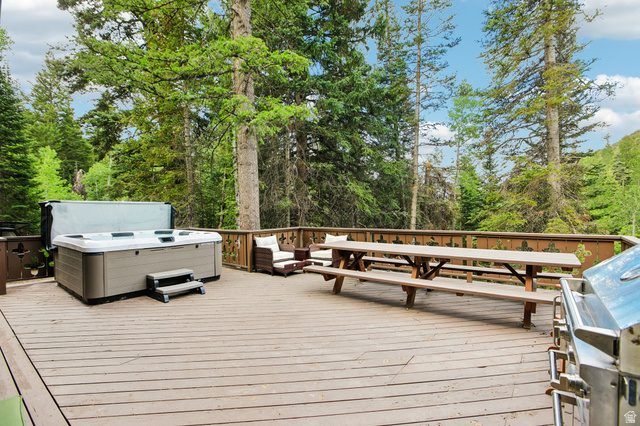 10205 East Moose Loop Road Salt Lake City, UT 84121 - Photo 39 of 50 Expansive outdoor deck featuring a hot tub, built-in picnic table, and surrounding natural foliage