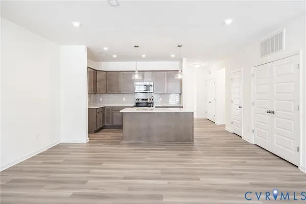 a large white kitchen with kitchen island a sink wooden floor and a refrigerator