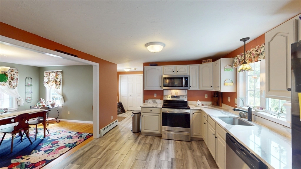 11 Valley View Circle Rutland, MA 01543 - Photo 9 of 38 a kitchen with stainless steel appliances a stove top oven a sink dishwasher a dining table and chairs with wooden floor