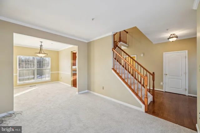 a view of an empty room with wooden floor and a living room