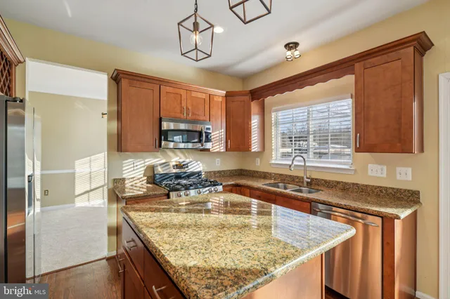 a kitchen with kitchen island granite countertop a sink a counter top space appliances and cabinets