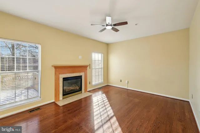 a view of an empty room with wooden floor and a fireplace
