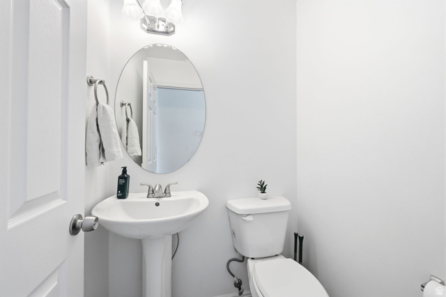 1816 River Bottom Road Springville, UT 84663 - Photo 17 of 37 White pedestal sink with a chrome faucet, oval mirror, and a wall-mounted light fixture
