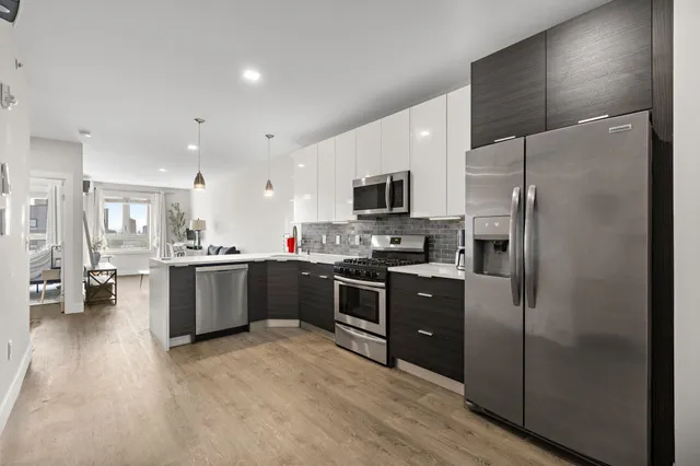 a large kitchen with a refrigerator a sink a stove top oven and white cabinets