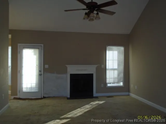 an empty room with windows and fireplace