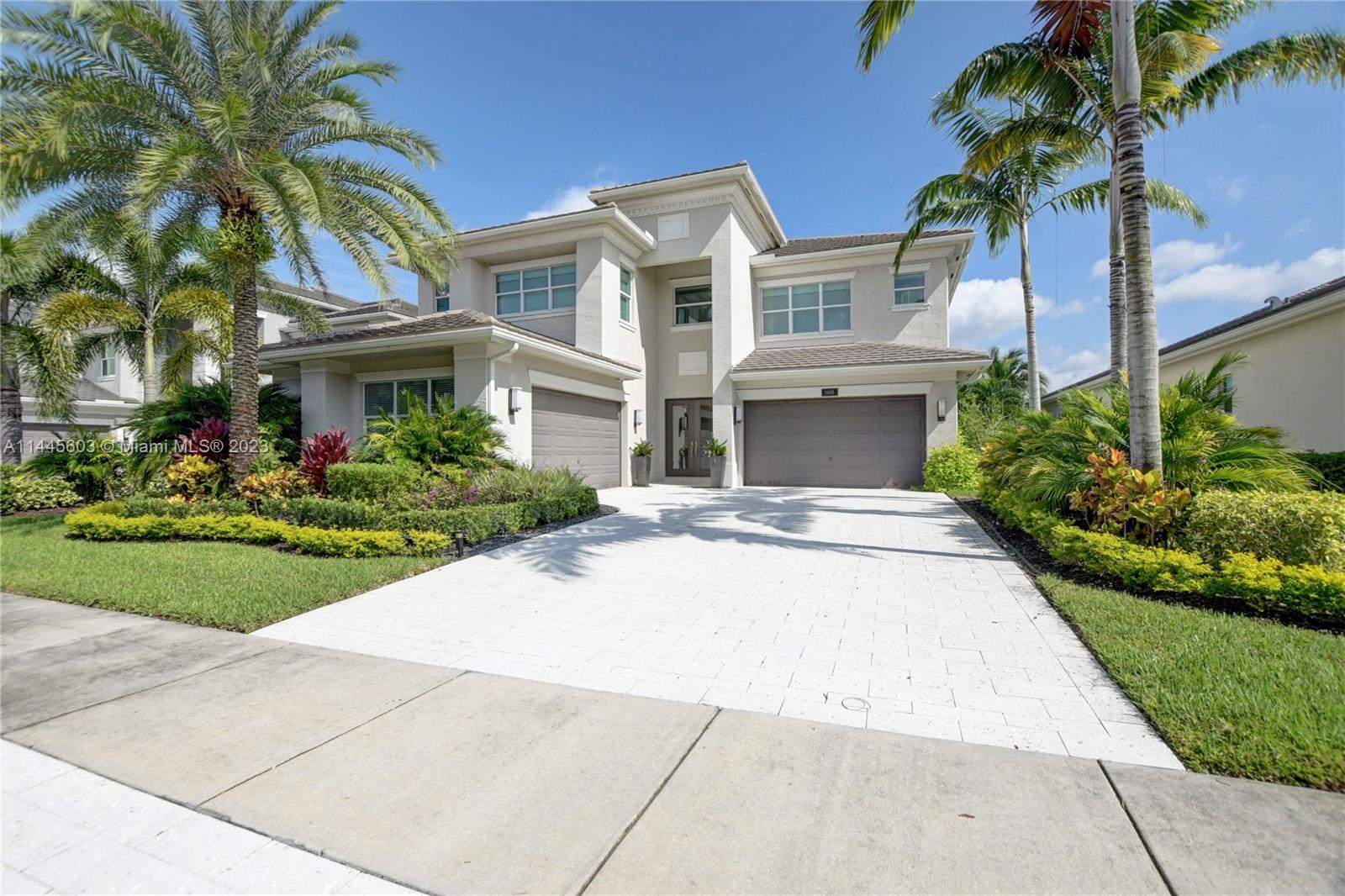 front view of house with a yard and palm trees