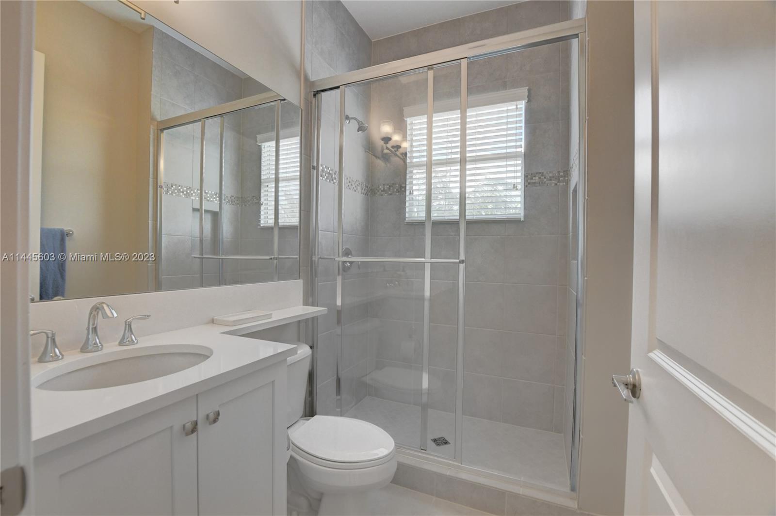 11655 Windy Frst Way Boca Raton, FL 33498 - Photo 35 of 69 a bathroom with a shower sink vanity mirror and toilet