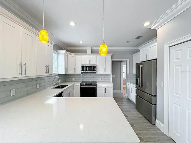 a kitchen with stainless steel appliances kitchen island granite countertop a refrigerator a stove a sink and a center island