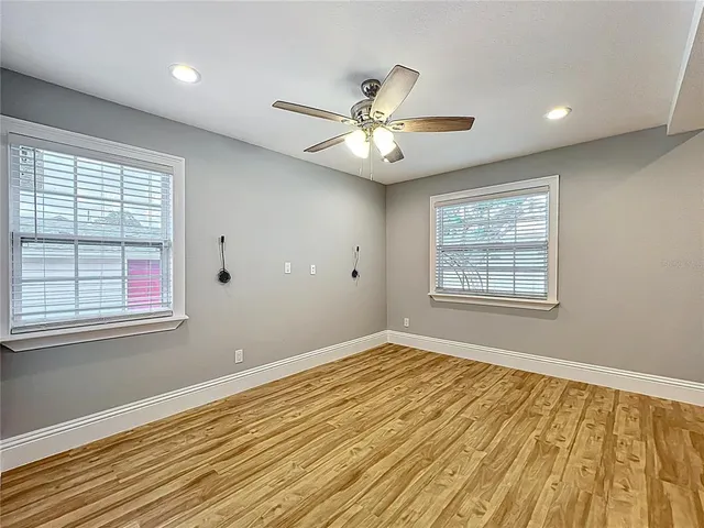 a view of an empty room with wooden floor and a window