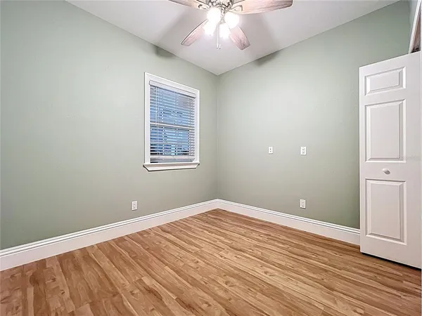 an empty room with wooden floor and chandelier fan