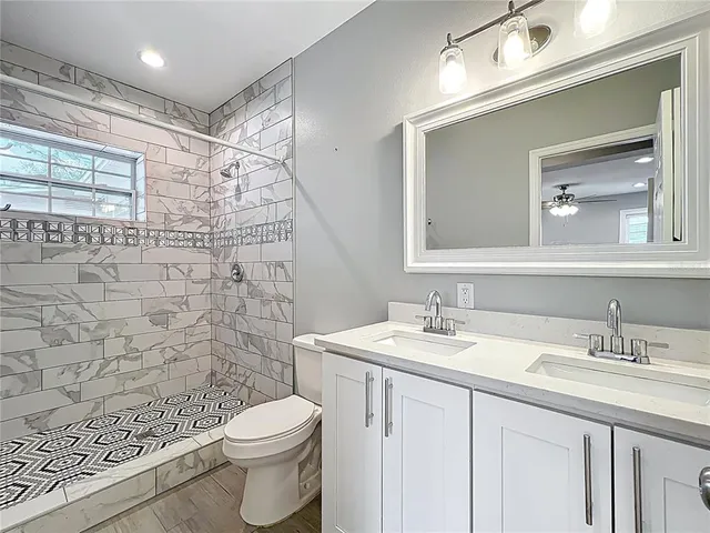 a bathroom with a granite countertop sink a toilet and a mirror