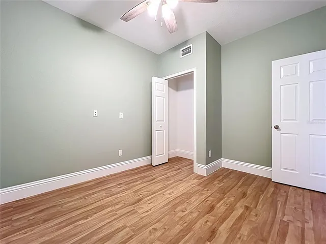 an empty room with wooden floor and chandelier fan