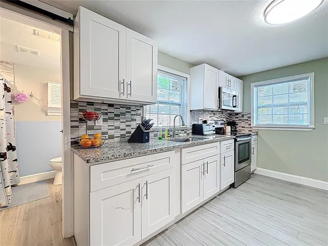 a kitchen with granite countertop white cabinets and white appliances