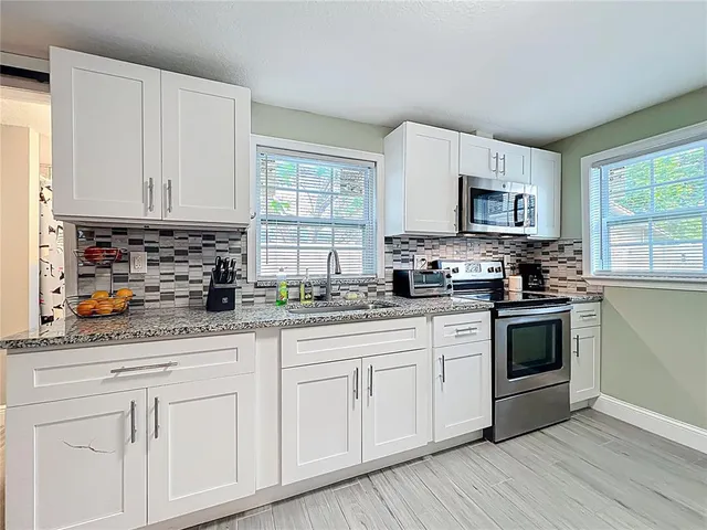 a kitchen with granite countertop white cabinets and white appliances