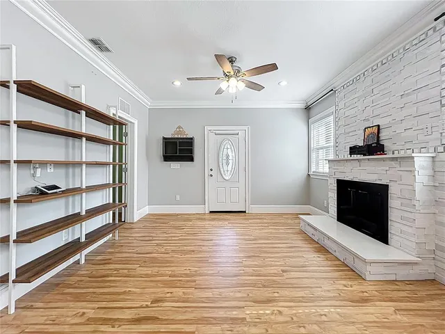 a view of an empty room with a fireplace and a ceiling fan