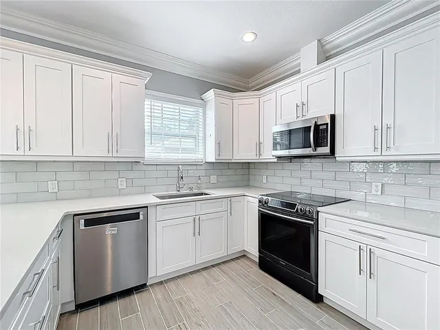 a kitchen with cabinets stainless steel appliances a sink and a window