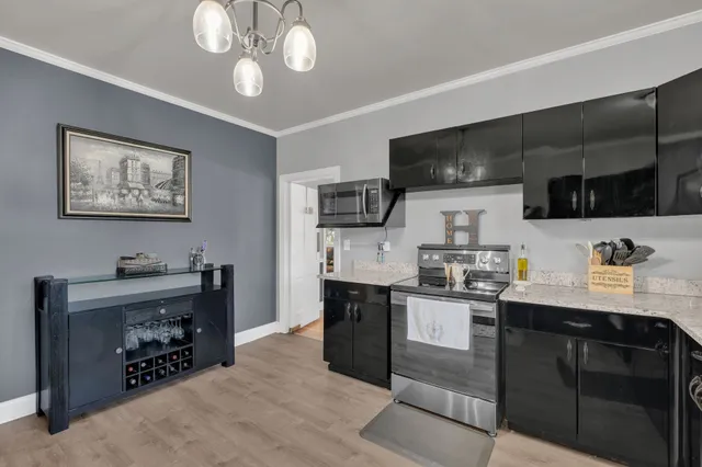 a kitchen with stainless steel appliances a sink dishwasher a refrigerator a microwave oven with cabinets and wooden floor