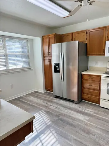 a view of a refrigerator in kitchen and an empty room with wooden floor