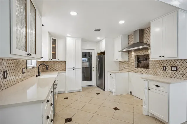 a large white kitchen with granite countertop lots of white cabinets and stainless steel appliances