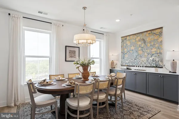 a dining room with wooden floor a chandelier a wooden table and chairs
