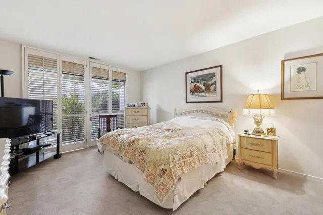 a spacious bedroom with a bed and a flat tv screen on wall
