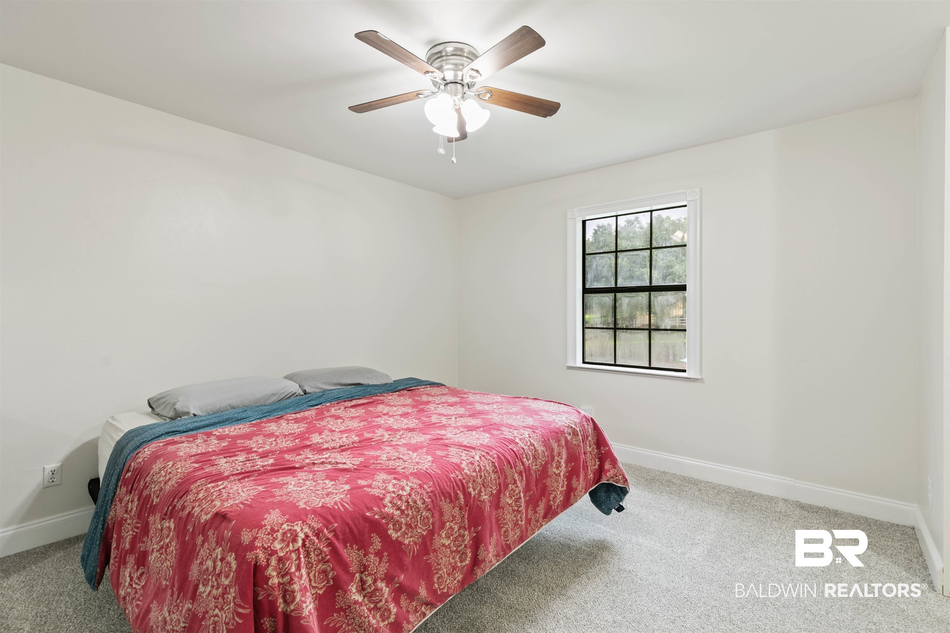 10420 Johnson Road South Mobile, AL 36695 - Photo 41 of 75 Neutral-toned room featuring a ceiling fan with integrated lighting, a window with white trim, and soft grey carpeting