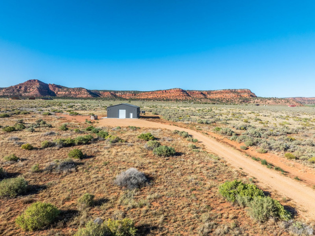 235 South Copper Road Kanab, UT 84741 - Photo 11 of 17 Steel-sided structure with two white garage doors, set against a backdrop of distant red rock formations