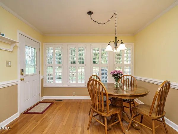 a dining room with furniture a chandelier and wooden floor