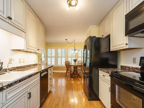 a kitchen with stainless steel appliances a stove a sink dishwasher a refrigerator and cabinets with wooden floor