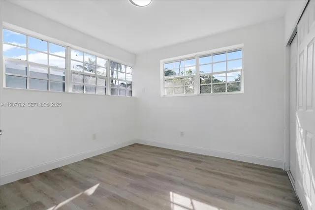 a view of an empty room with wooden floor and a window