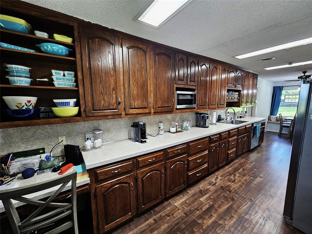 220 North Calhoun Street Groesbeck, TX 76642 - Photo 4 of 24 a kitchen with stainless steel appliances granite countertop wooden cabinets a stove top oven a sink and dishwasher