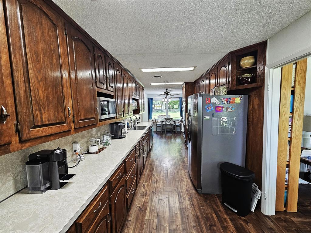 220 North Calhoun Street Groesbeck, TX 76642 - Photo 5 of 24 a kitchen with stainless steel appliances granite countertop a refrigerator a sink and wooden cabinets