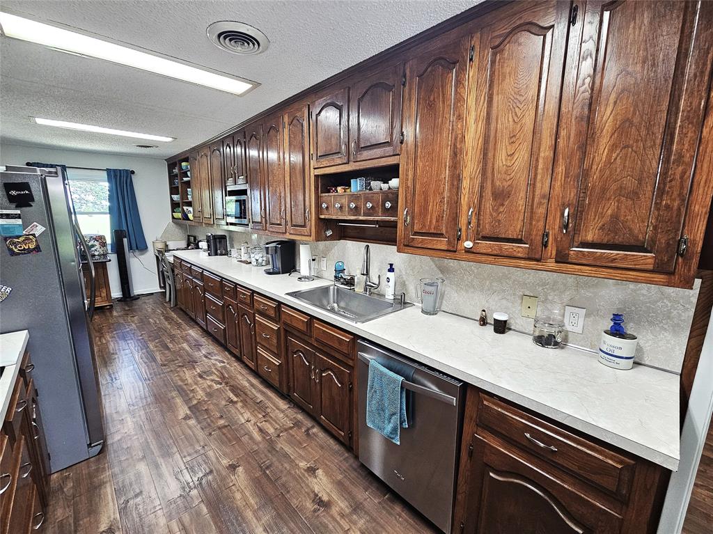 220 North Calhoun Street Groesbeck, TX 76642 - Photo 7 of 24 a kitchen with granite countertop wooden cabinets a sink and dishwasher