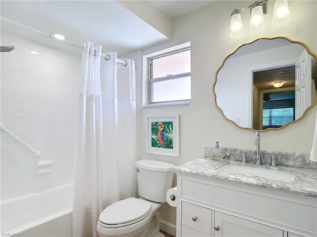 a bathroom with a granite countertop toilet a sink a mirror and a bathtub