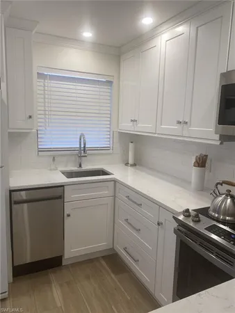 a kitchen with white cabinets stainless steel appliances and sink