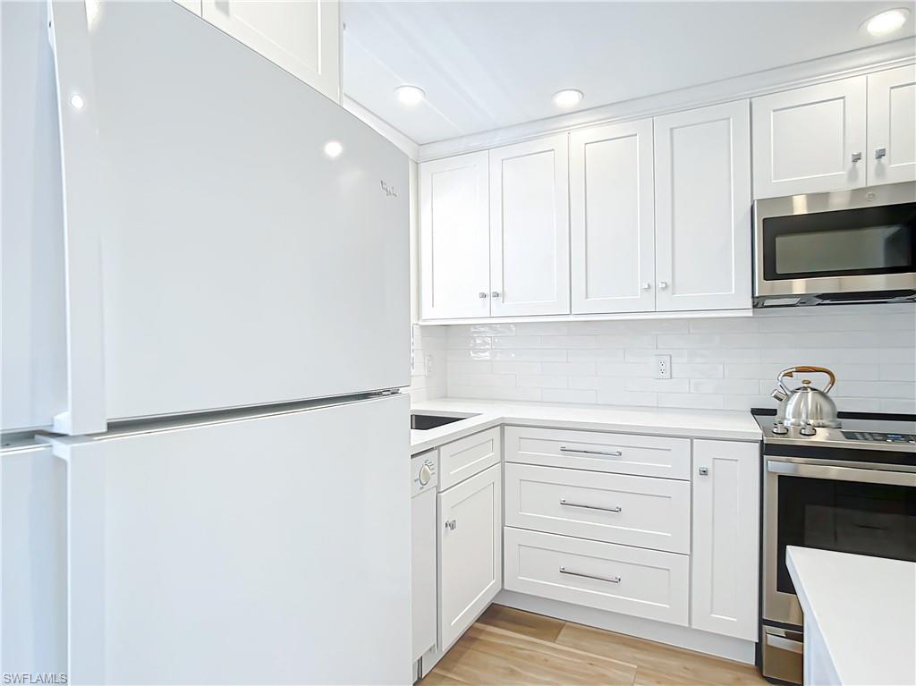 180 Turtle Lake Court, Unit 206 Naples, FL 34105 - Photo 6 of 50 a kitchen with white cabinets and a refrigerator
