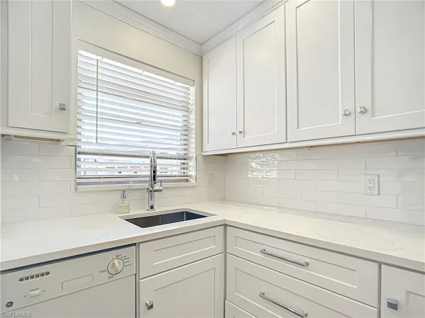 a kitchen with white cabinets and a window
