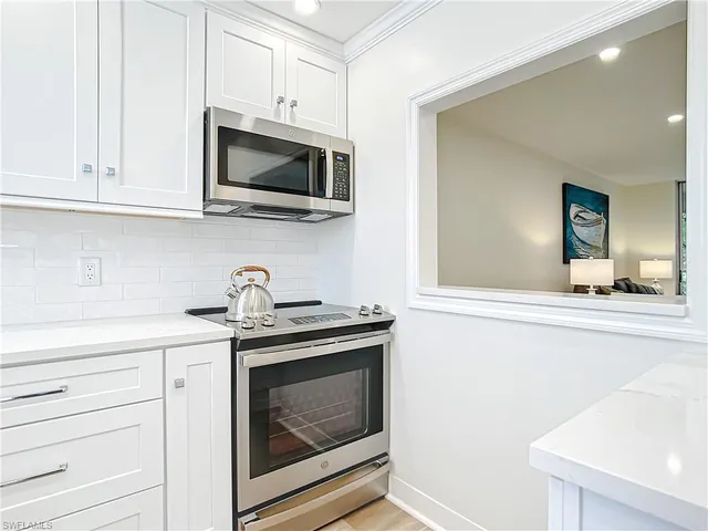 a kitchen with stainless steel appliances granite countertop white cabinets a stove and a sink