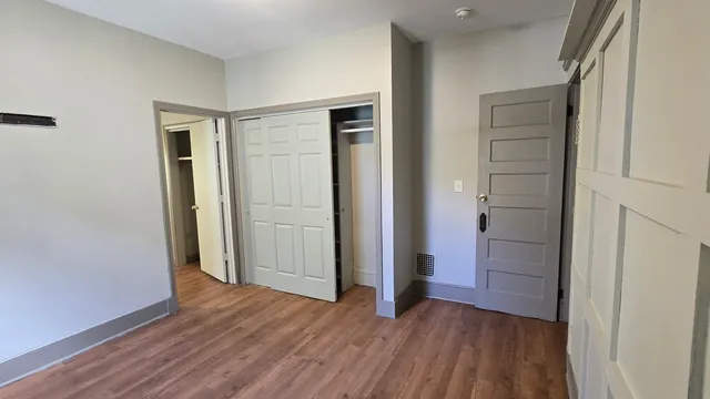 an empty room with wooden floor & closet area