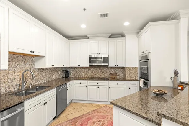 a bedroom with a bed a computer on desk and a potted plant