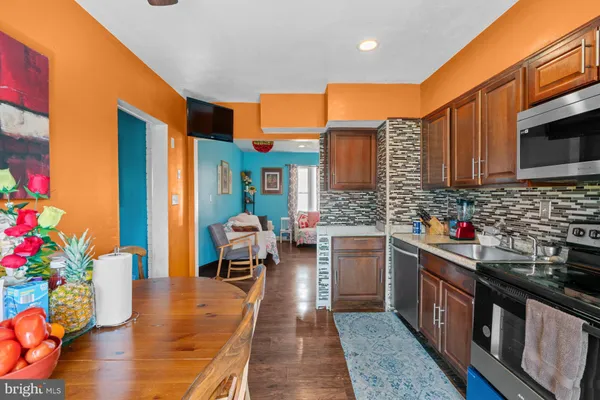 a kitchen with stainless steel appliances granite countertop a refrigerator a stove top oven a sink dishwasher and dining table with wooden floor