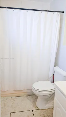 a white toilet sitting next to a shower curtain