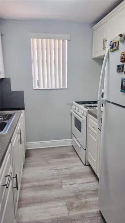 a view of a kitchen with wooden floor and electronic appliances