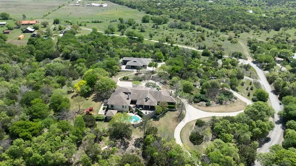 an aerial view of residential house with outdoor space and trees all around